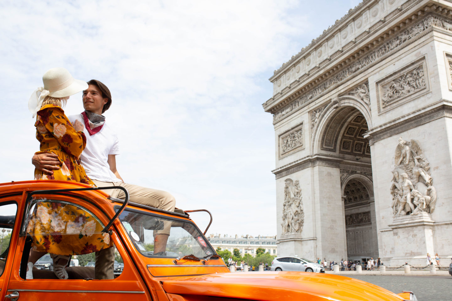 couple in orange car in front of the Arc de Triomphe