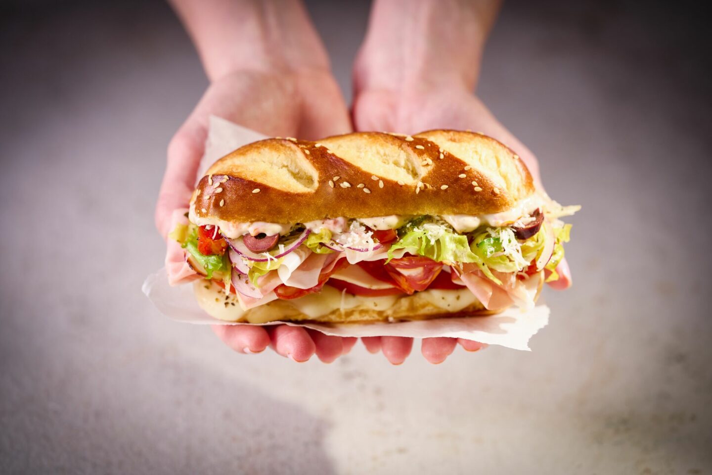 Hands Holding St Pierre Pretzel Roll Italian Grinder